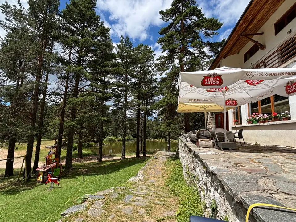 Semkovo Hut terrace with outdoor tables beside the pine forest.