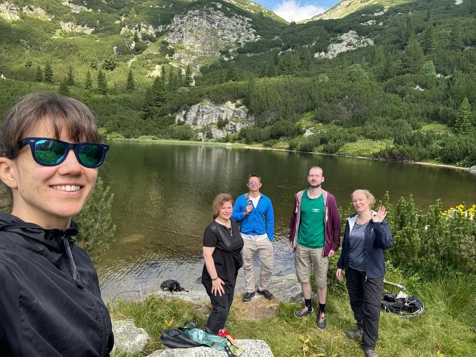 Five walkers by Suhoto Lake beneath the mountain slopes.