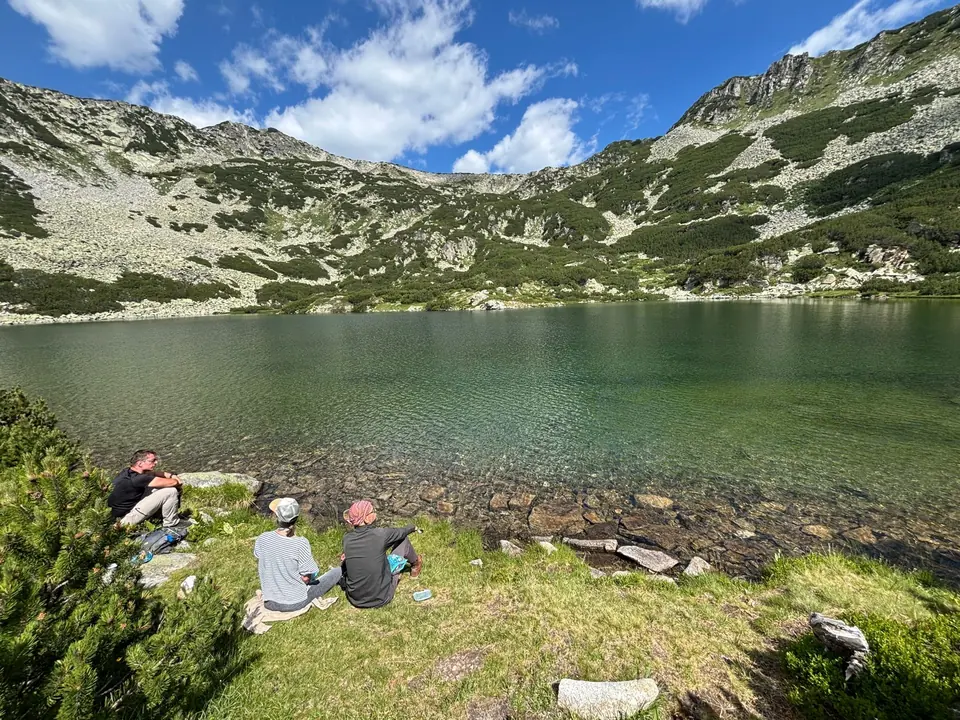 Walkers picnicking beside Vapsko Lake in its rocky mountain bowl.