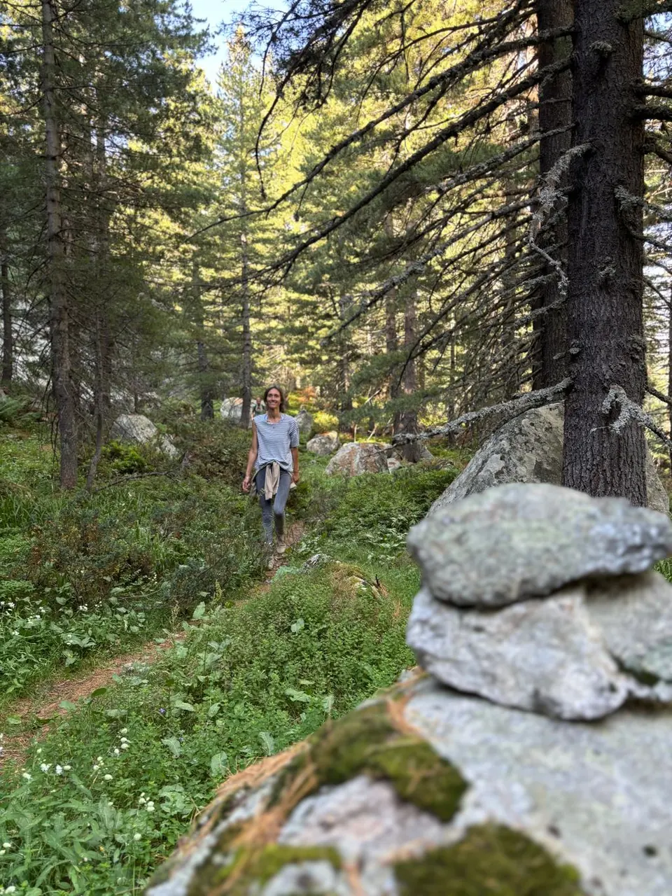 Small stone cairn and a walker on a forest path during the Vapsko outing.