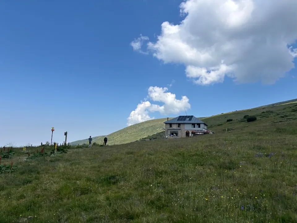 Macedonia Hut across an open mountain meadow.