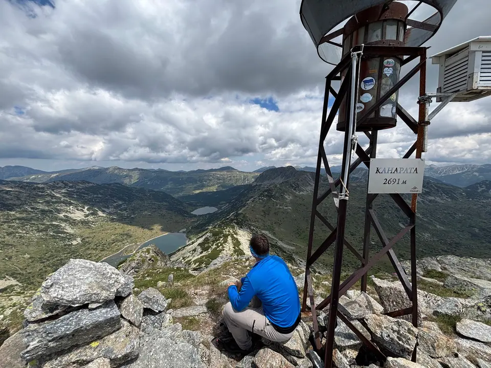 Kanarata summit marker reading 2,691 m, a seated walker and the lake basins beyond.